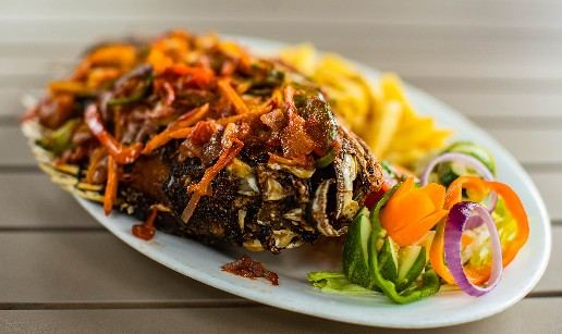 Whole grilled fish platter with vegetables and chips